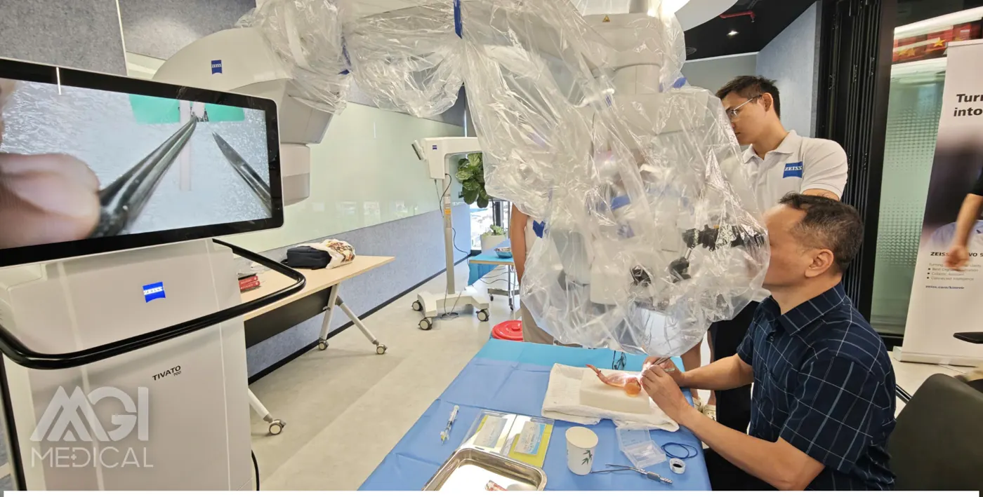 A participant working under the operating microscope, with the view shown at the same time on the screen beside the table. Photo: MGI Medical.